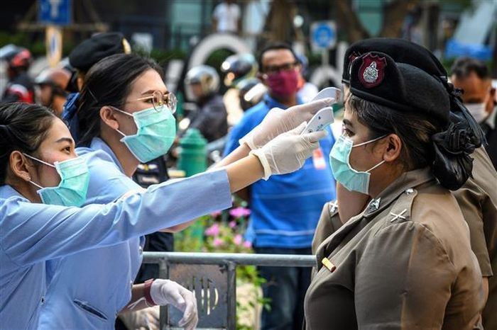 Nhân viên y tế kiểm tra thân nhiệt cho cảnh sát ở Bangkok, Thái Lan. Ảnh: AFP/TTXVN