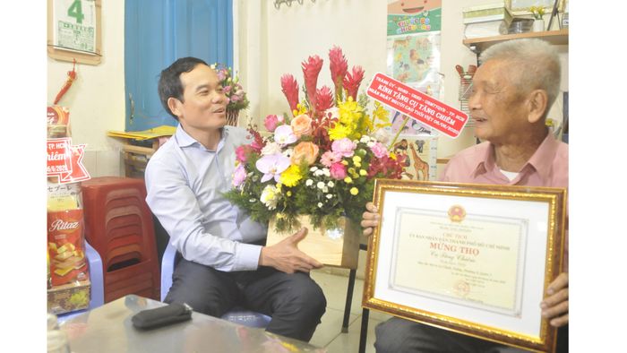 Phó Bí thư Thường trực Thành ủy TPHCM Trần Lưu Quang tặng hoa mừng thọ cụ Tăng Chiêm. Ảnh: CAO THĂNG