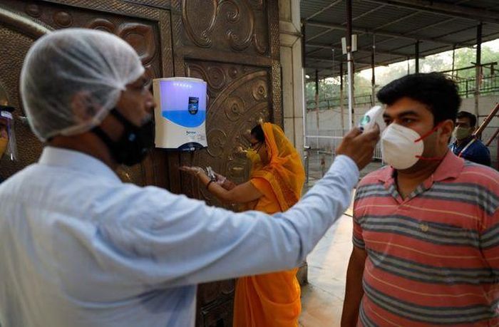 Kiểm tra thân nhiệt trước khi vào đền thờ ở thủ đô New Delhi (Ảnh: REUTERS)