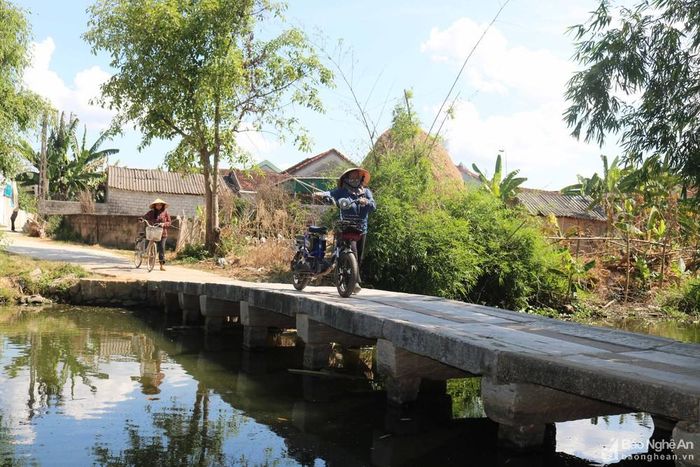 Do cầu không có lan can, nên nhiều người phụ nữ khi qua cầu thường dắt xe để đảm bảo an toàn. Ảnh: Huy Thư
