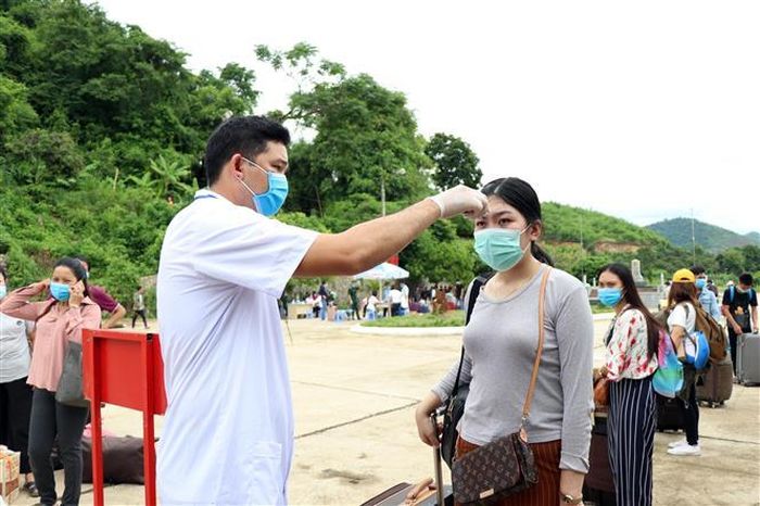 Lực lượng chức năng kiểm tra thân nhiệt lưu học sinh Lào tại cửa khẩu Chiềng Khương, tỉnh Sơn La. Ảnh: Hữu Quyết - TTXVN