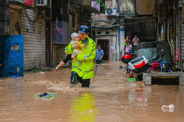 Chính quyền địa phương đã phải sơ tán gần 500.000 người tại 26 quân, huyện gần lưu vực sông Dương Tử. Ảnh: Chen Xingyu, một sĩ quan cảnh sát giải cứu một em bé từ một khu phố bị ngập lụt.
