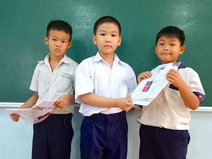 Bé Ngô Hải Long-lớp 2/1, Trường Tiểu học Lương Thạnh (giữa) tặng áo mới cho hai bạn có hoàn cảnh khó khăn trong lớp từ chính số tiền tiết kiệm của mình. Ảnh: M.T