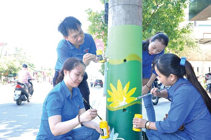 Các bạn trẻ vẽ hoa lên cột điện. Ảnh: QH