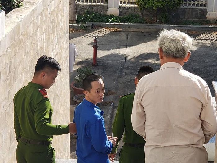 Bị cáo Phạm Văn Dương (giữa) và người cha tranh thủ trò chuyện ngay bậc thềm trụ sở tòa án. Ảnh: TÂM AN