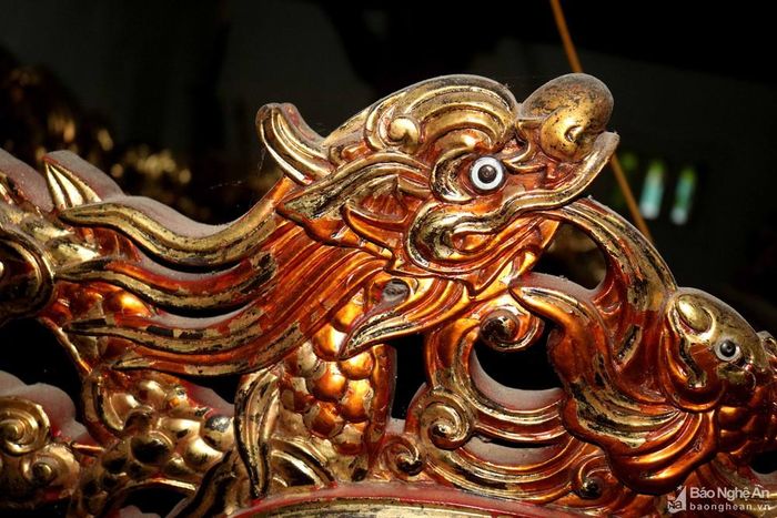 Với chiếc kiệu này, các đòn khiêng dọc, ngang đều là những "thân rồng", các tiểu tiết xung quanh kiệu cũng được trang trí hình rồng uyển chuyển. Trong ảnh: Hình cá chép chầu rồng trên kiệu cổ. Ảnh: Huy Thư