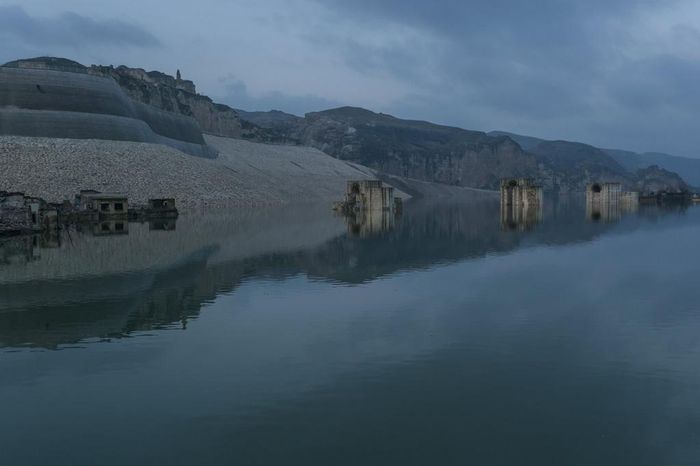  Sau nhiều năm chính quyền cảnh báo nhưng chưa hành động, hồi kết của thung lũng Hasankeyf đã bất ngờ ập đến. Tháng 8/2019, chính phủ ra lệnh đóng các cửa đập Ilisu và xả nước từ một hồ nằm xa hơn về phía thượng nguồn. "Chúng tôi đã hy vọng nước sẽ không đổ về. Chúng tôi đã không tin rằng ngôi làng sẽ bị nhấm chìm", Remziye Nas, người làng Bzere, nơi nước đã dâng đến thềm nhà, cho biết. Ảnh: New York Times. 