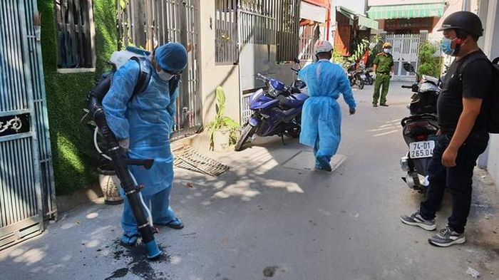  Nhân viên y tế phun thuốc khử trùng quanh nhà bệnh nhân. Ảnh: Thanh Đức. 