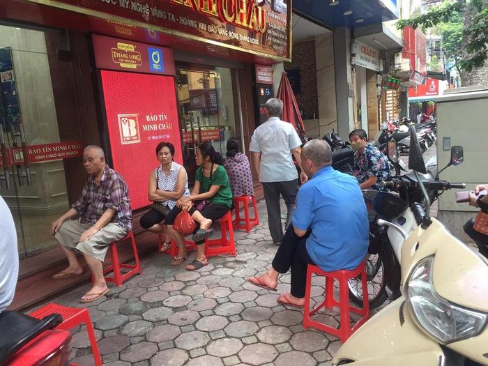 Cửa hàng vàng trên phố Trần Nhân Tông chưa mở cửa, một số khách hàng ngồi đợi để vào giao dịch.