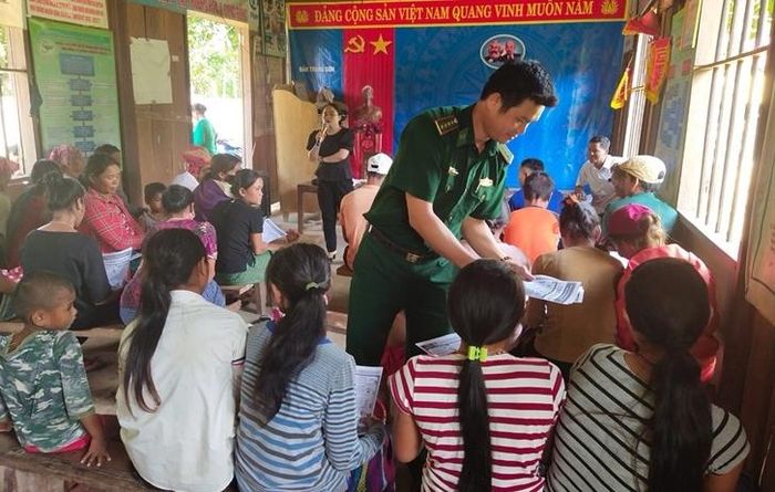 Cán bộ Đồn Biên phòng Làng Mô phát tờ rơi tuyên truyền về phòng chống dịch Covid-19 cho người dân. Ảnh: Thành Phú