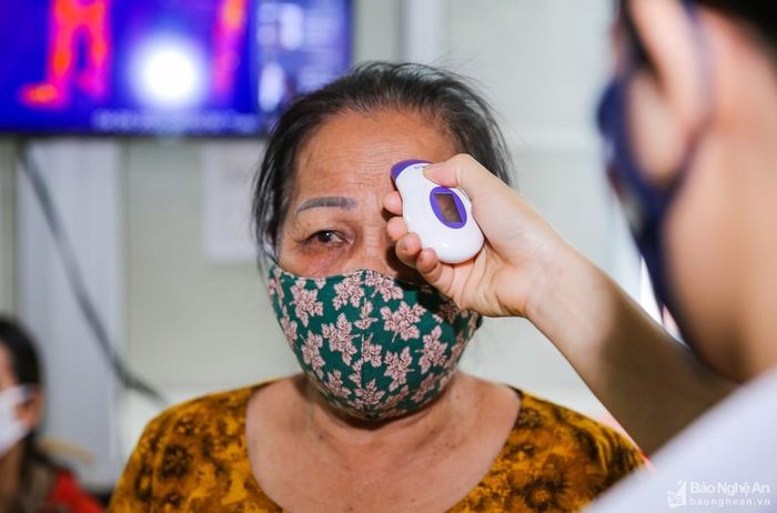 Người dân được rửa tay sát khuẩn và đo thân nhiệt trước khi vào viện. Ảnh: Đức Anh