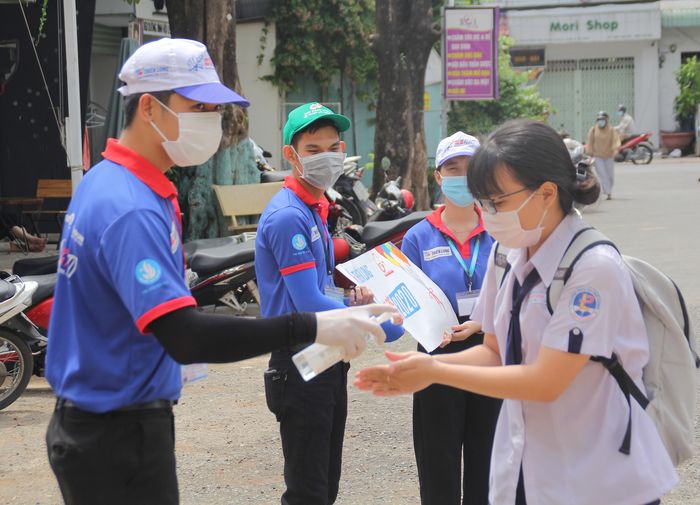 Các bạn sinh viên Học viện Bưu chính viễn thông trực tại điểm thi Trường THPT Phước Long (quận 9, TPHCM) giúp thí sinh sát khuẩn tay trước giờ thi