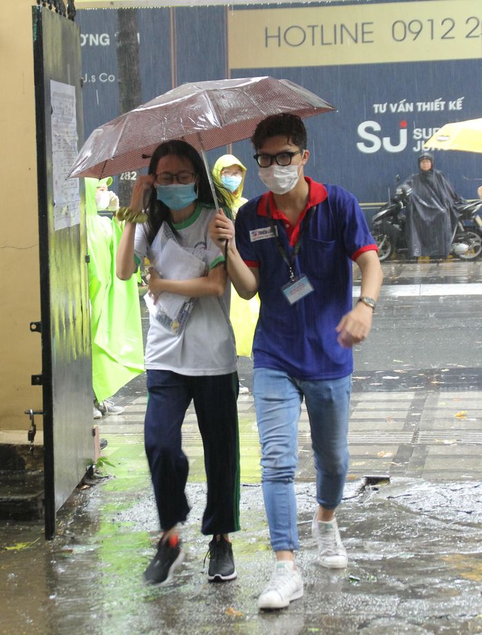 Tình nguyện viên đội mưa "tiếp sức" sĩ tử tại điểm thi THPT Marie Curie (quận 3)