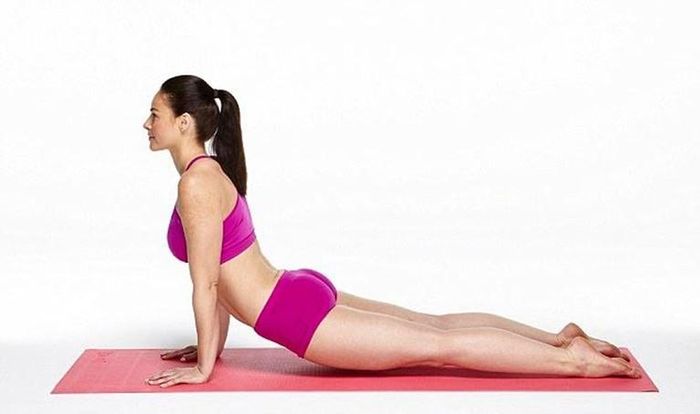 Để thực hiện tư thế rắn hổ mang, trước tiên, bạn hãy nằm úp bụng, hai chân duỗi thẳng áp xuống sàn, trán cúi thấp trên sàn. Ảnh: thanhnien.
