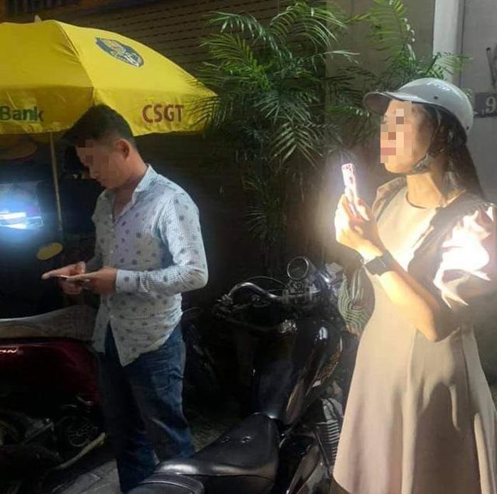 Hình ảnh người phụ nữ ngồi sau anh T sử dụng điện thoại di động để quay quá trình xử lý của tổ công tác.
