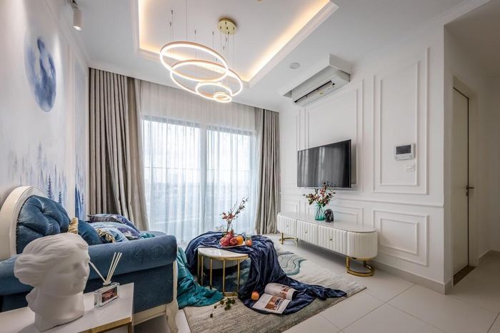 Điểm nhấn của phòng khách nằm ở đèn trần và các chi tiết trang trí tường độc đáo. Rèm cửa và giấy dán tường cũng được thiết kế tông xanh trắng.