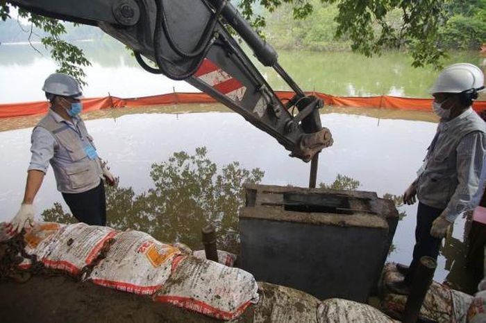 Khối bê tông cuối cùng đang được công nhân dùng máy thủy lực ép xuống đáy hồ