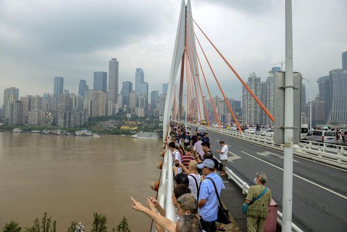 Người dân hiếu kỳ tập trung trên một cây cầu để quan sát nước lũ sông Trường Giang đang dâng cao ở mức kỷ lục. Ảnh: Getty.