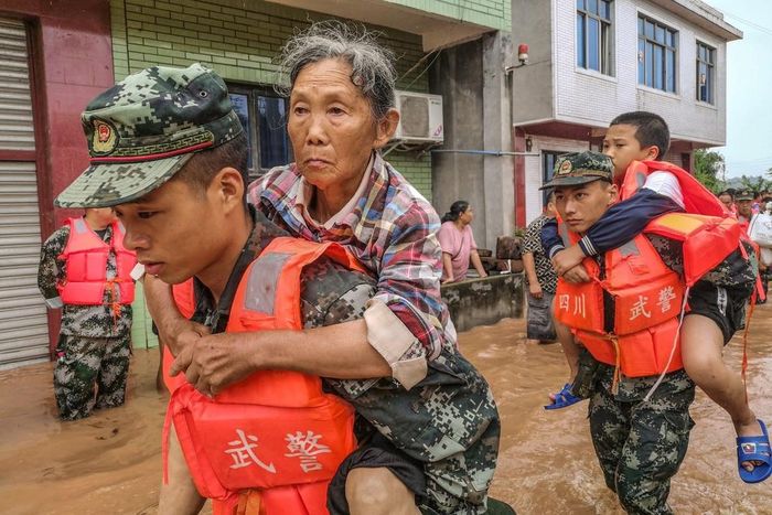 Cảnh sát Trung Quốc sơ tán người già và trẻ em ra khỏi những khu vực nguy hiểm. Hơn 100.000 người buộc phải sơ tán tránh lũ. Ảnh: Getty.