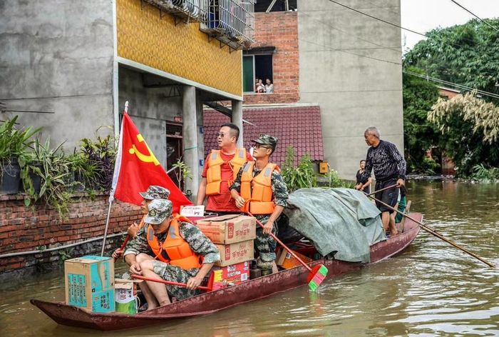 Cảnh sát và các tình nguyện viên chèo thuyền cung cấp lương thực hỗ trợ cho người dân bị mắc kẹt bởi lũ lụt. Ảnh: Gettty.