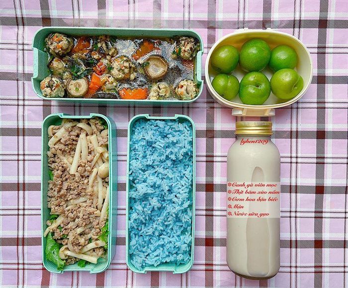 Chị Lý chia sẻ để có những phần cơm hấp dẫn như vậy phải dậy sớm từ 6h để nấu thức ăn. Phần trà hoặc nước hoa quả được nấu từ tối hôm trước rồi để tủ lạnh. Trong ảnh là bữa cơm gồm canh gà viên mọc, thịt băm xào nấm, cơm hoa đậu biếc, mận và nước sữa gạo. Về món cơm hoa đậu biếc, bạn chỉ cần đun nước nóng nóng rồi thả hoa vào 5 phút chắt lấy nước và nấu cùng với gạo.