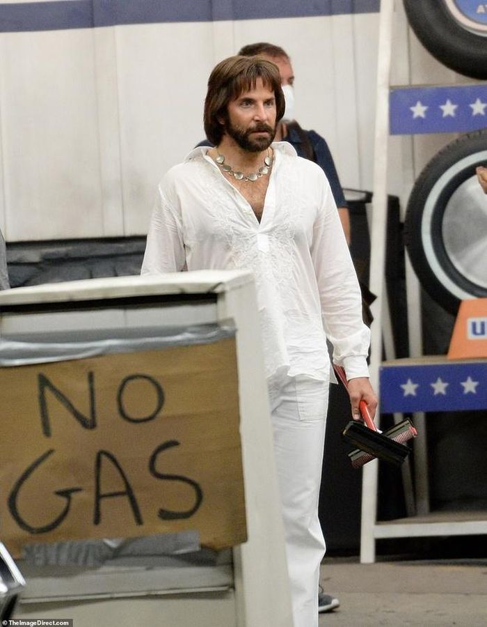 Trên phim trường, Bradley Cooper trông khác lạ khi đội tóc giả ngang vai, mặc áo họa tiết, quần ống loe và giày da phong cách thập niên 1970.