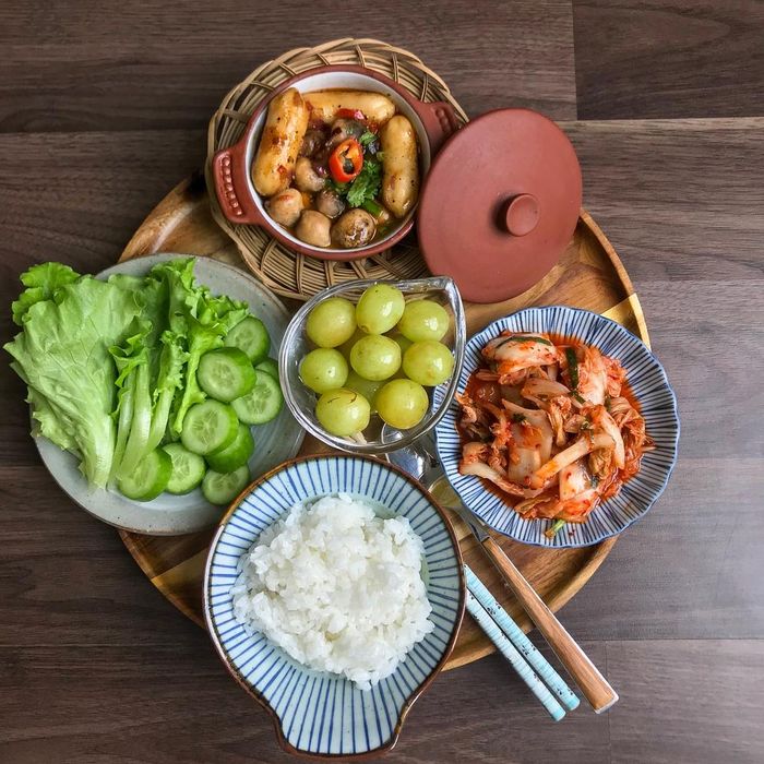Nếu là tín đồ của các món ăn Hàn Quốc, mâm cơm này sẽ là lựa chọn dành cho bạn. Bánh gạo sau khi luộc sơ qua nước sôi sẽ kho cùng nấm rơm, trang trí thêm ớt và rau thơm. Bạn có thể tham khảo công thức sốt theo tỷ lệ 4 muỗng nước tương, một thìa tương ớt, 1/2 thìa đường, muối, tiêu để món ăn có hương vị đậm đà nhất. Đi kèm món chính là kim chi, dưa chuột, rau tươi và không thể thiếu hoa quả tráng miệng.