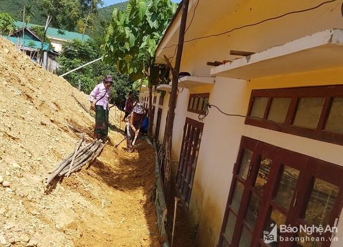 Phụ huynh mang vật liệu có sẵn trong nhà đến để giúp nhà trường kè lại các điểm sạt lở. Ảnh: Kiều Quang