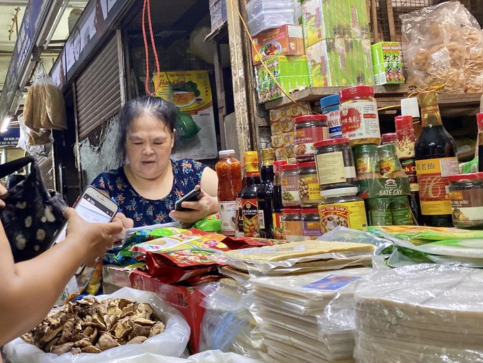 Trong số hơn 20 loại gia vị tại quầy S.T, xuất hiện một số chai, lọ bao bì hoàn tiền là tiếng Trung Quốc, Thái Lan, không có nhãn phụ tiếng Việt. Những sản phẩm ấy được người bán nói qua là tương, nước chấm, có giá từ 15.000 – 50.000 đồng/ chai