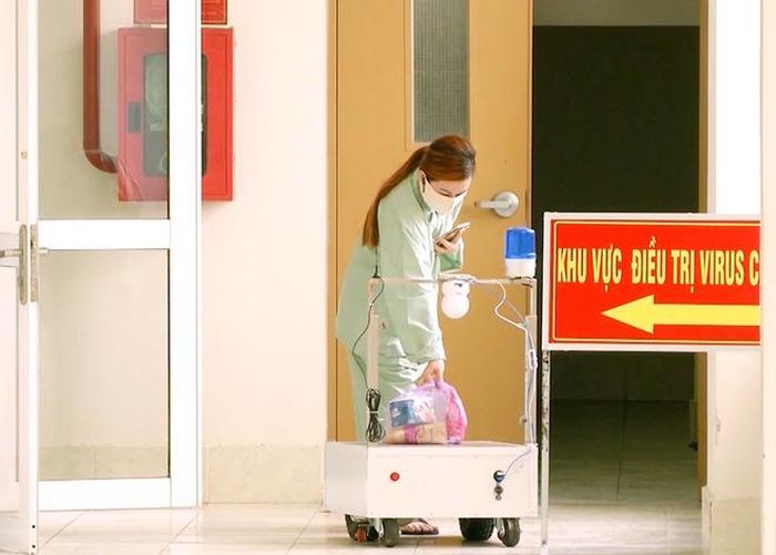 Nữ bệnh nhân nhận nhu yếu phẩm do robot mang vào.