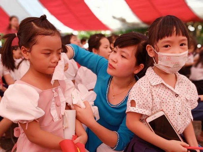 Nhiều em học sinh lớp 1 được giáo viên chủ nhiệm lau mồ hôi để các em bớt nóng. Ảnh: Oanh Trần. 