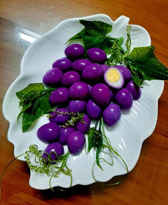 Chùm nho tím. Theo chị Mai, chị luộc trứng rồi bóc vỏ, thả vào nồi nước lá cẩm đã sôi khoảng 3 phút là sẽ có màu tím. Món ăn được trang trí cùng rau su su.