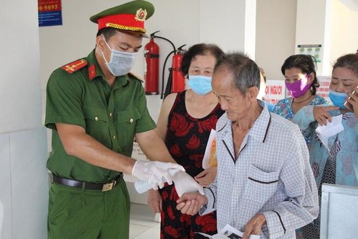 Người dân đến nhận cháo được phun nước diệt khẩn, đảm bảo công tác phòng ngừa dịch bệnh.