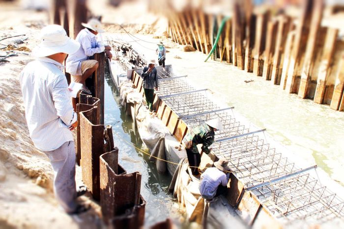 Kỹ thuật viên đang hướng dẫn công nhân tạo móng làm kè biển chắn sóng và triều cường tại xã đảo Nhơn Hải, TP Quy Nhơn (Bình Định)