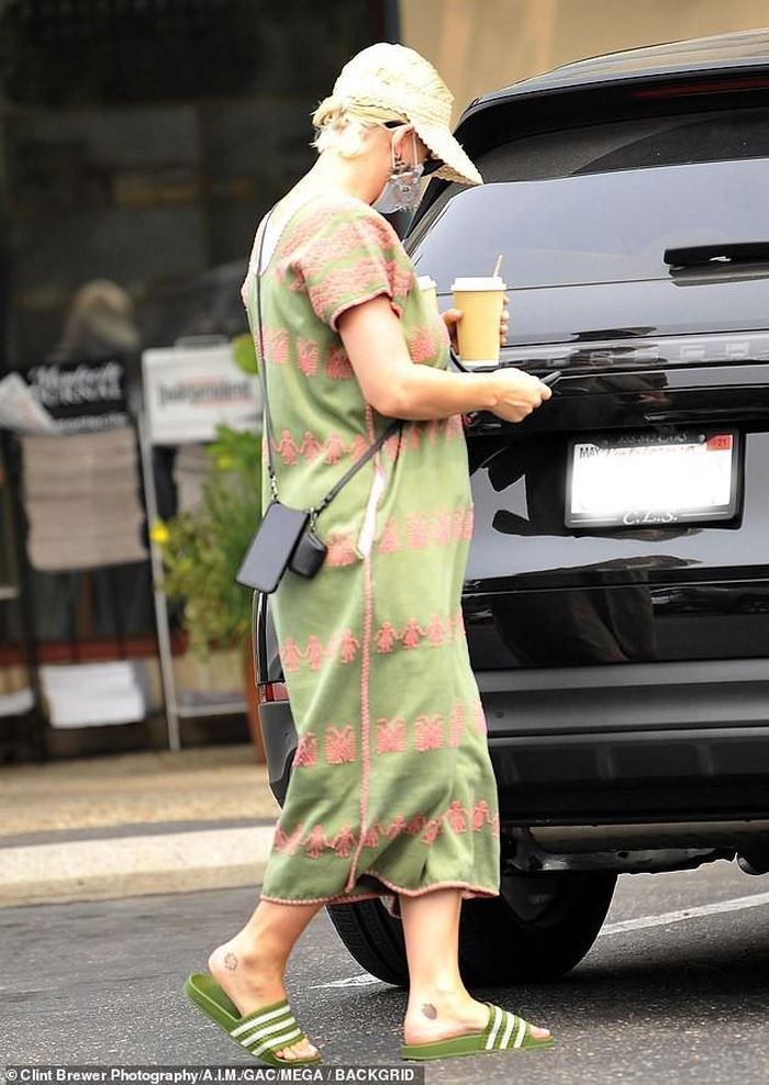 Bà mẹ bỉm sữa mới mặc váy dài màu xanh rêu phong cách Bohemian của thương hiệu Pippa Holt, có giá 601,87 bảng Anh (17,8 triệu đồng), đi dép lê của Adidas, đội mũ che nắng và bịt khẩu trang kín mít.