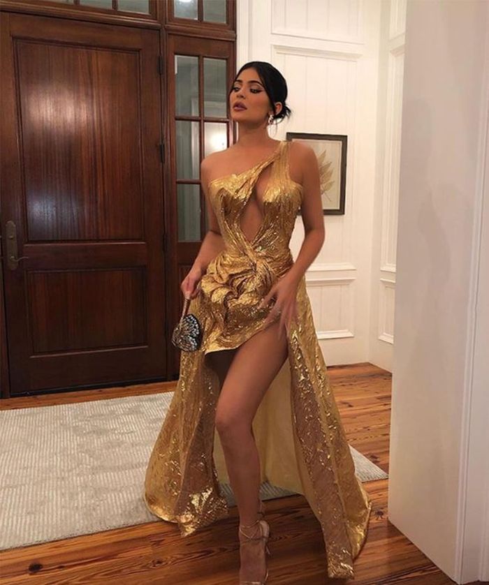  Cô gái sinh năm 1997 diện váy trễ vai màu vàng đồng của J'Aton Couture với đường xẻ cao đến đùi tới dự đám cưới Hailey Baldwin và Justin Bieber. Kylie phối cùng giày cao gót, túi hình cánh bướm độc đáo. Vẻ ngoài của cô được Vogue khen là sành điệu hơn hẳn trước đây. Ảnh: @kyliejenner. 