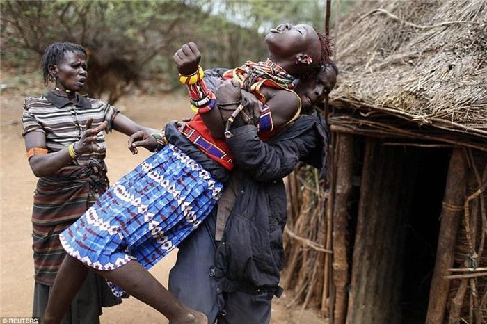 Những người đàn ông thuộc bộ lạc Pokot kèm chặt một sắp phải làm lễ cưới với một người trong bộ lạc. 