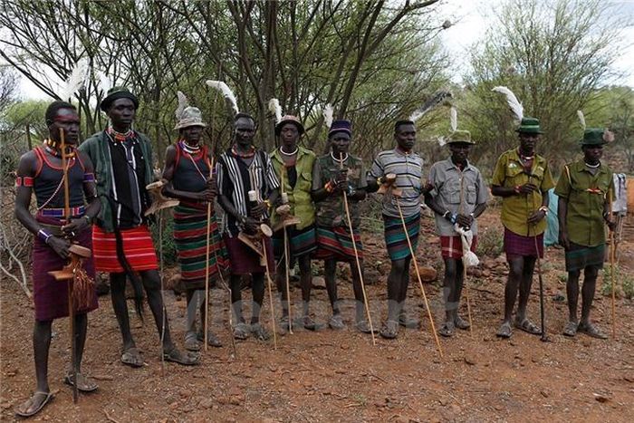 Người Pokot đứng canh gần nhà một cô bé sắp trở thành vợ của một người trong số họ.