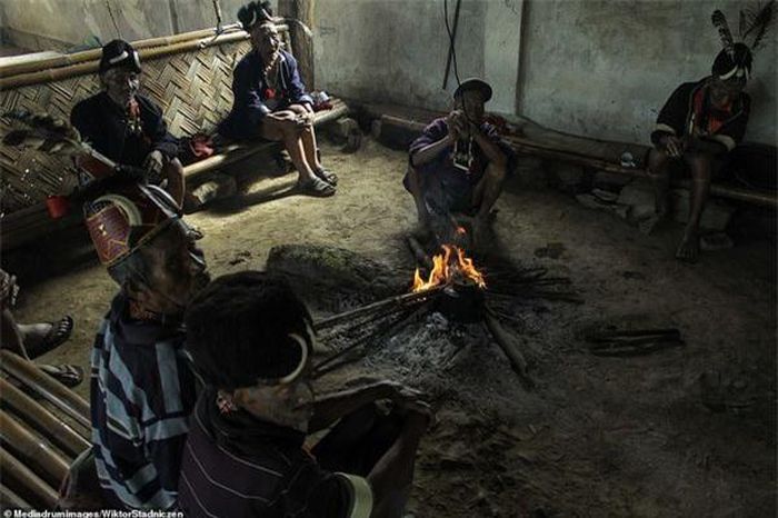 Người Konyak vẫn sống một cuộc đời thô sơ trong những ngôi nhà làm từ tre trúc. Trong ảnh là 7 người già trong bộ lạc đang ngồi quanh một đống lửa.