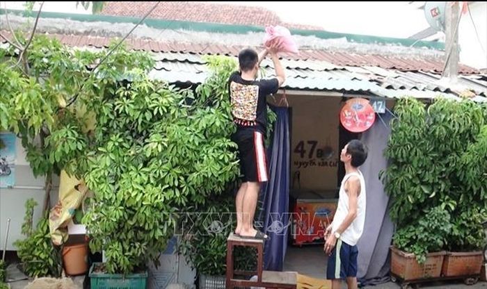 Người dân trên địa bàn phường Nam Lý, thành phố Đồng Hới, Quảng Bình che chắn bao tải cát lên mái nhà ứng phó với gió bão.