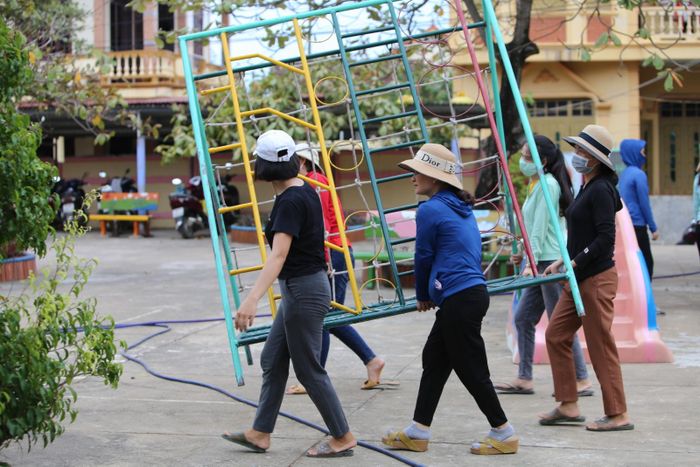 Các giáo viên mầm non di chuyển đồ chơi ngoài trời của trẻ để chống bão