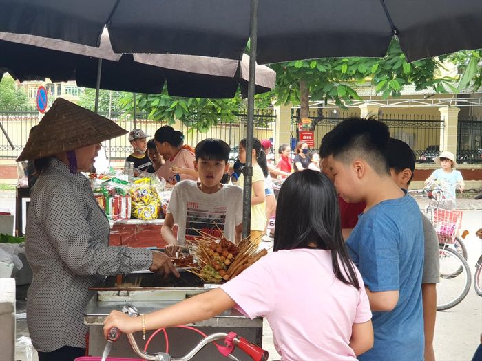 Học sinh tụ tập, mua đồ ăn vặt trước cổng trường. Ảnh: Long Vân