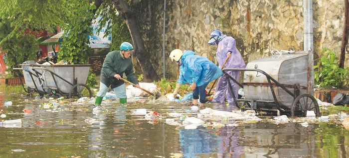 Công nhân Xí nghiệp cây xanh công viên và Thoát nước đô thị làm việc trên đoạn đường Mai An Tiêm, phường Tân Dân, TP Việt Trì ngập bùn đất và rác thải do mưa lớn.