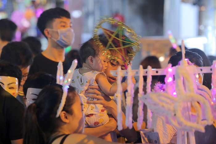 Các em nhỏ được người thân bế lên vai để ngắm cảnh phố phường nhộn nhịp