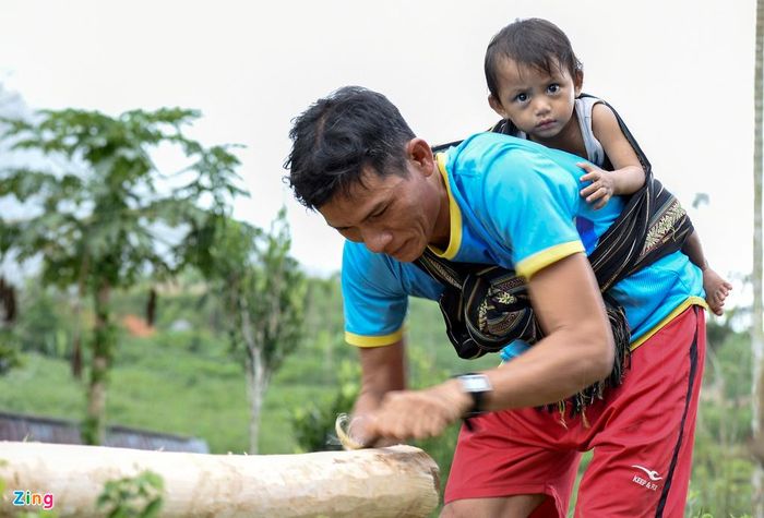 Ông Đinh Văn Hùng (Sơn Bua, Sơn Tây) vừa địu con, vừa đẽo cây gỗ keo làm nhà sàn. "Vốn quý nhất ở vùng đất này con người thật thà, mến khách, khí hậu mát mẻ quanh năm, đất đai tốt phù hợp để trồng cây ăn quả, dược liệu gắn với phát triển dịch vụ du lịch", ông Đinh Quang Ven, quyền Chủ tịch UBND huyện Sơn Tây, cho hay.
