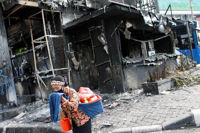 Tổng thống Widodo, người từng là thị trưởng Jakarta và nhà sản xuất đồ nội thất một thời, tự nhận ông luôn hướng đến lợi ích của người lao động. Trên cương vị tổng thống, ông đã tập trung vào phát triển kinh tế, đặc biệt là xây dựng đường sá, cảng và sân bay. Trong ảnh, người bán đồ uống dạo lấy tay che mũi, miệng khi đi qua đồn cảnh sát bị đốt cháy gần dinh tổng thống ở Jakarta hôm 9/10.