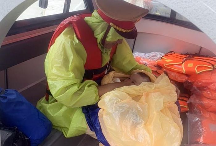 Cháu bé 2 tháng tuổi được đưa lên ca nô an toàn.