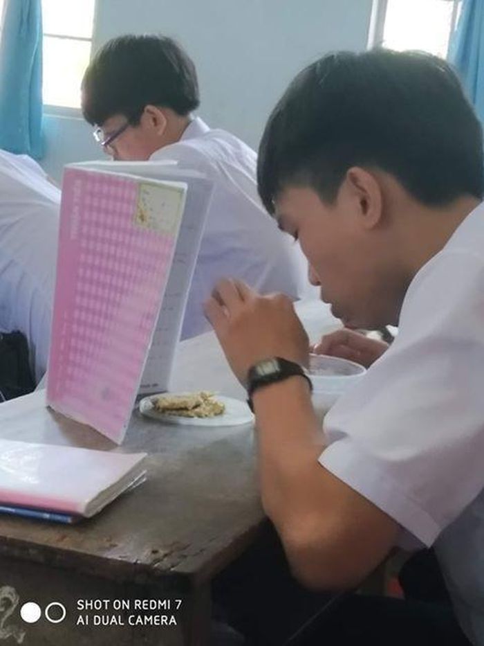 Một nam sinh khác to gan lớn mật ăn vụng trong lớp, cậu đã khéo léo dựng cao cuốn vở lên để che đi màn ăn vụng trong lớp học của mình.