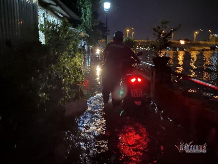 Người dân bì bõm lội nước dẫn bộ xe bị chết máy qua đoạn đường ngập