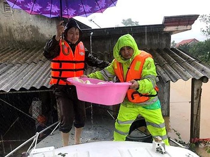 Đồng chí CSGT Nguyễn Thông đưa cháu bé sơ sinh trong ngôi nhà bị ngập lụt lên xuồng cứu hộ an toàn, ngày 9-10. 